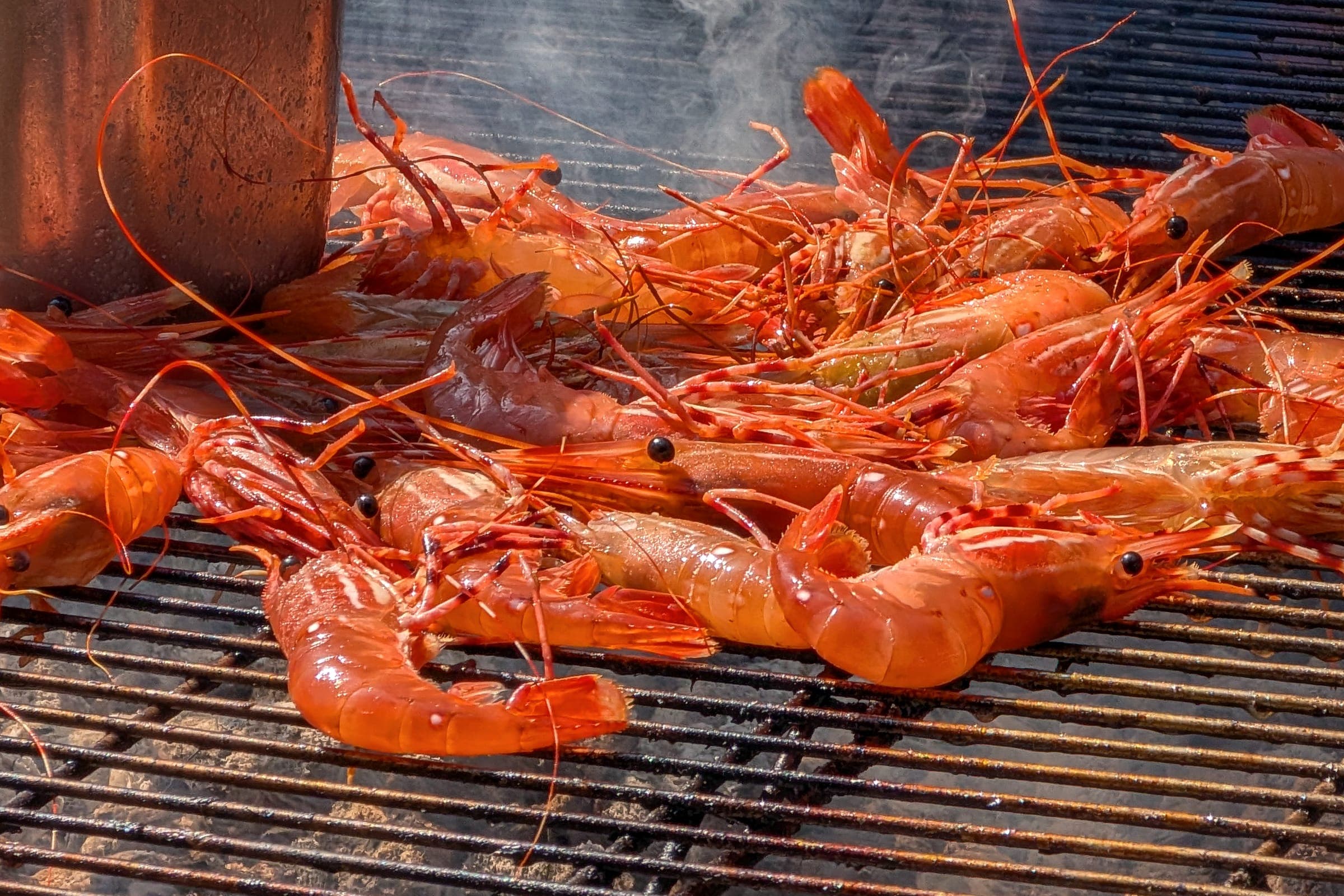 Whole prawns, head-on and shell-on, turning red on a hot grill